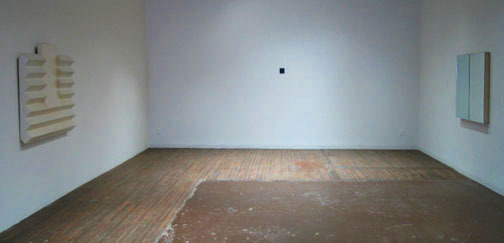 Two pale objects hanging on white walls across from each other.