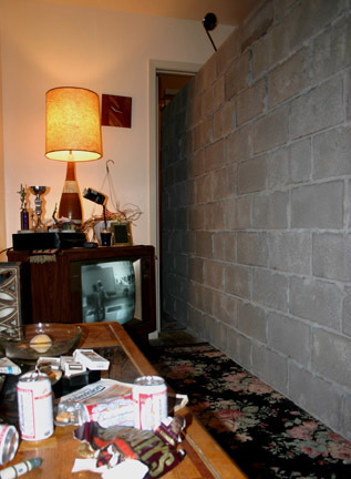 An image of a crowded room with various objects against a tall concrete wall.
