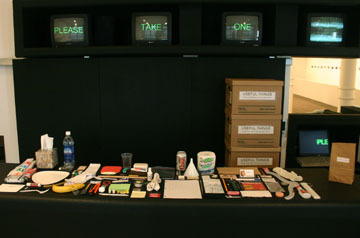 A table covered with various items and signs above stating, "Please Take One".
