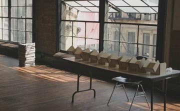 A room with big open windows and boxes sitting on a table.