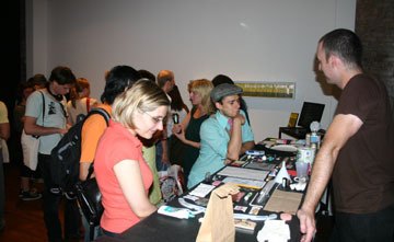 A group of people walking around a room, looking at objects.