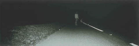 A person standing far away on a dark road.