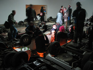 A group of people walking around on top of the undercarriage of many cars.