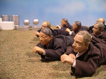 A bunch of sculptures of people crawling on the ground.