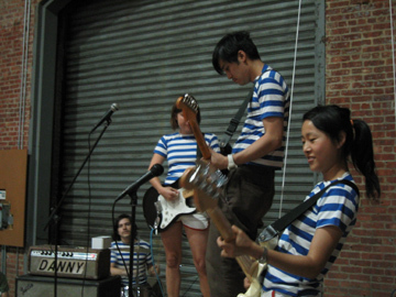 Three people playing on guitars wearing striped t-shirts.