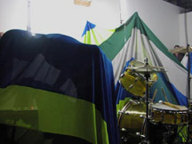 A drum set surrounded by green, blue and white tarps.