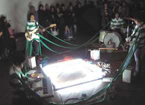 A group of people in striped t-shorts performing in a circle surrounded by people watching.