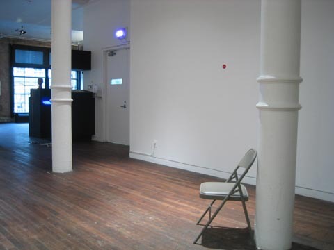 A gallery with a chair in the middle of the space.