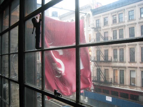 An image of a big red flag waving outside of a building, with "SI" on it.
