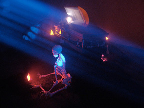 A skeleton floating the air in front of a big blue light.