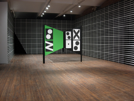A black and white walled room with a green sculpture in the middle.