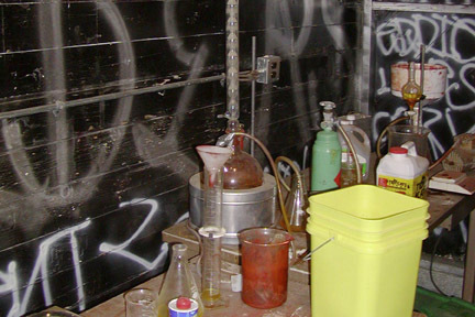 A photo of a meth lab with black spray painted walls.