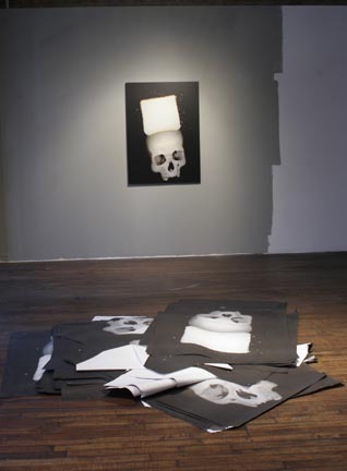 A room with photos of a skull and paper placed on the wall and around the floor.