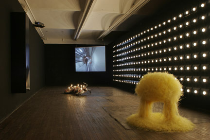A room with lots of small lights coming from the walk, and sculptural works on the floor.