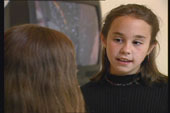 A close-up of a young child talking with another person.