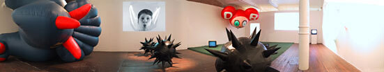 A panoramic view of the exhibition, including an inflated figure and other sculptural works.